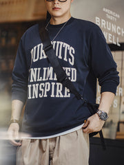 詳細画像
「フロック加工のロゴプリントと起毛素材の滑らかな肌触りをクローズアップ。背面の刺繍アーチロゴや裾のラバープリントタグもディテールとして特徴的。」
モデル画像
「モデルがフロック加工ロゴプリント長袖Tシャツを着用し、ドロップショルダーとクルーネックが特徴のアメリカンストリートスタイルを披露。」