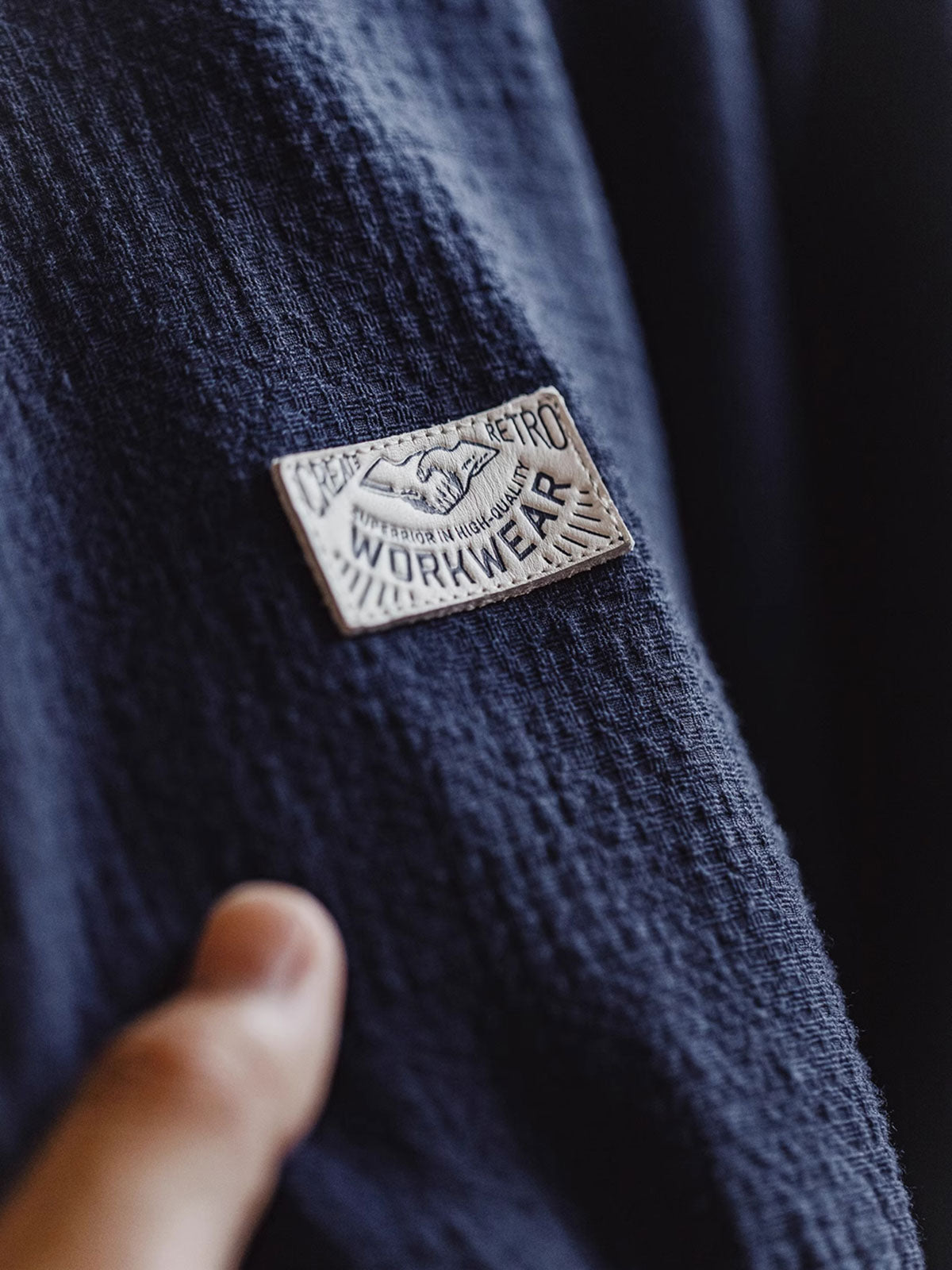 フーディの襟元にある竹製オリーブ形ボタンとレザーのシルクスクリーンプリントヴィンテージロゴの詳細画像