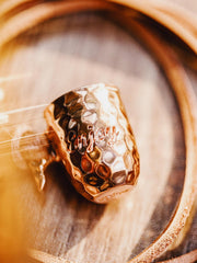 製品画像
ハンドメイドで仕上げられたハンマーテクスチャーが美しい銅カップペンダント。全体的にヴィンテージ感を強調したデザインで、時間の経過とともに味わい深いアンティークな色合いが楽しめます。レザーコード付きでカジュアルからフォーマルまで幅広く対応可能なアクセサリー
詳細画像
職人の手作業によるハンマーテクスチャーのディテールと、丁寧に彫刻された英文字刻印が印象的な銅カップペンダント。細部にまでこだわりが詰まった表面デザインが、独自のクラフトマンシップを感じさせます。自然な酸化による変化が楽しめる素材感も魅力