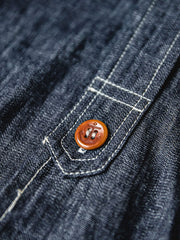 海軍インスパイアのCPOデニムシャツのアンカーボタンのディテールとフラップポケットをクローズアップ。厚手のコットン生地が強調されています。