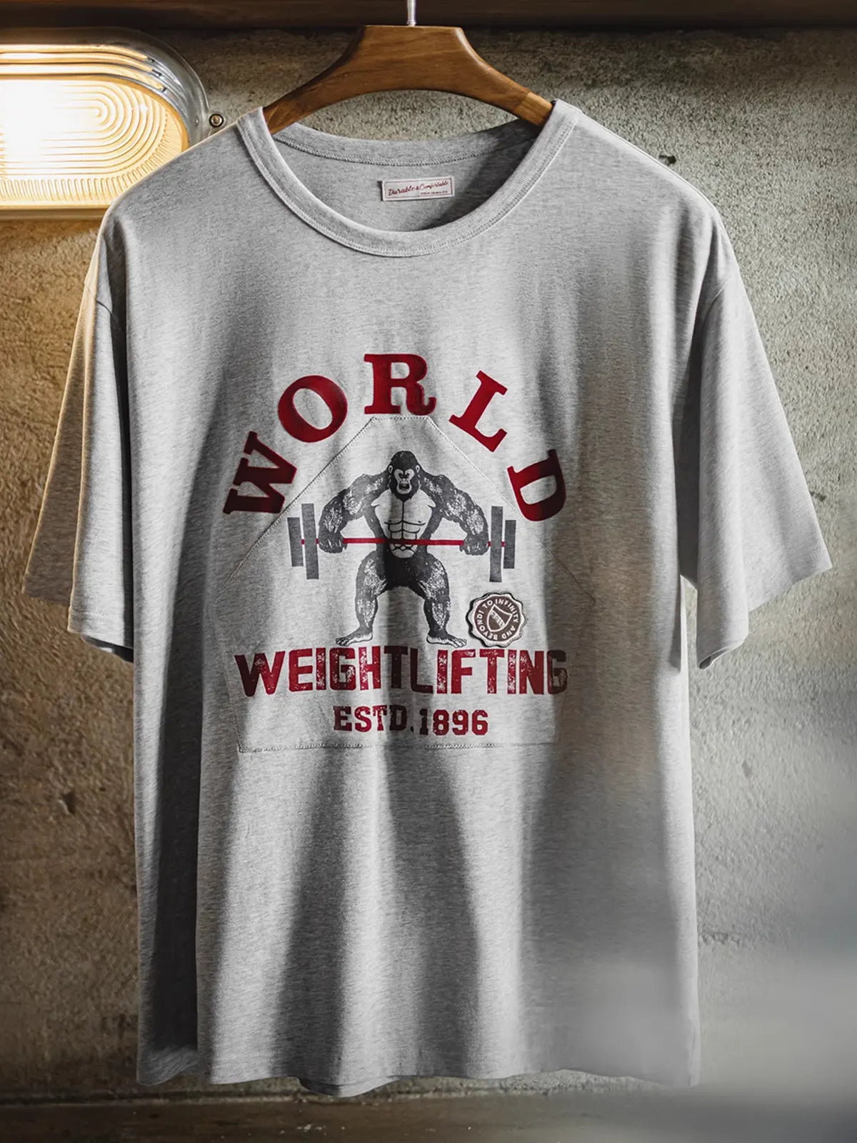 猿がバーベルを持ち上げるグラフィックを背負ったグレーヘザーTシャツ