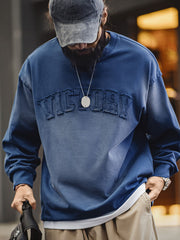 モデルがヴィンテージレターアップリケスウェットをデニムと合わせ、ラフなスタイリングを披露