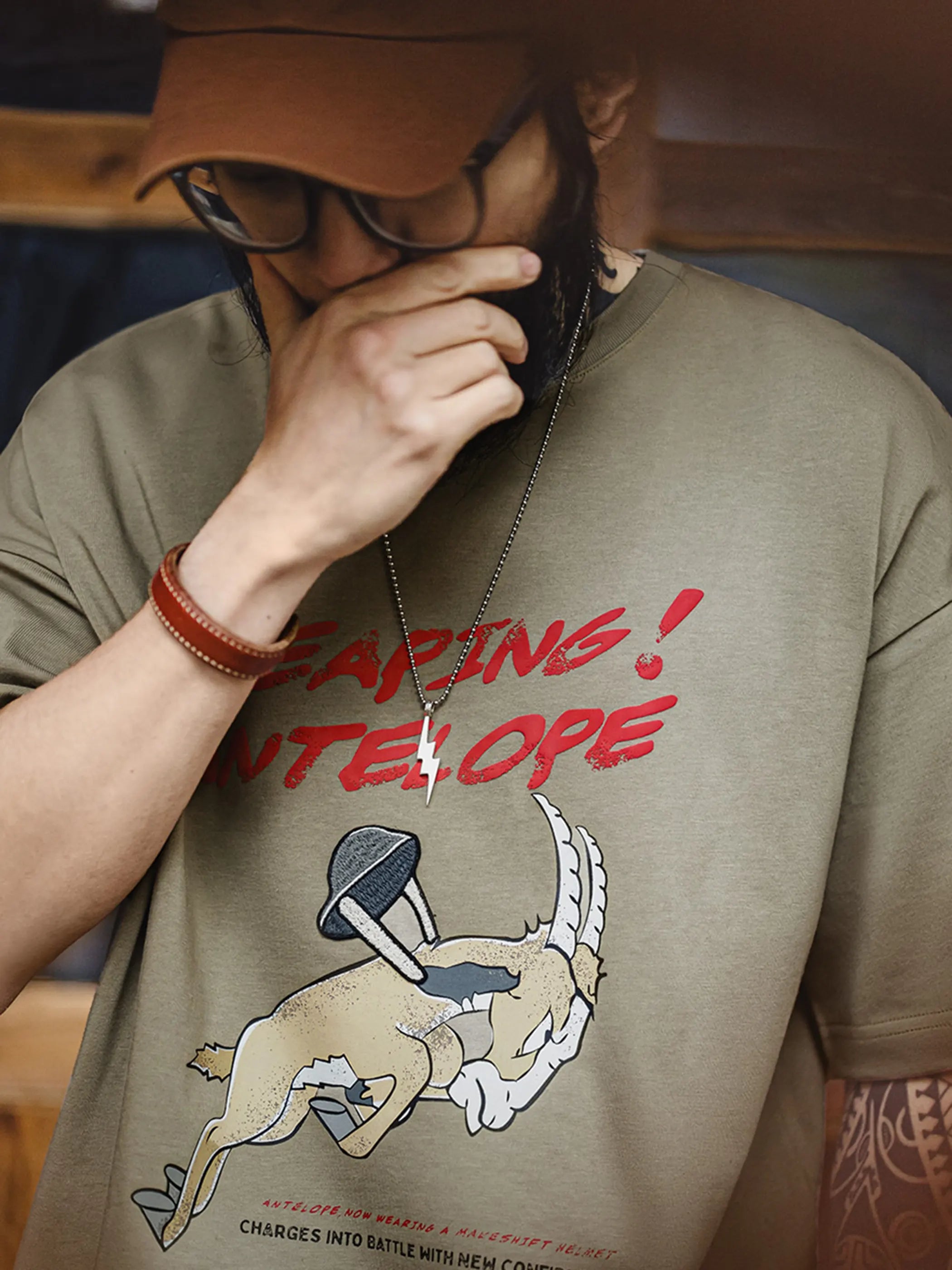 跳ねるアンテロープの刺繍と発泡プリントを施したミリタリーグリーンのTシャツ