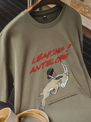 跳ねるアンテロープの刺繍と発泡プリントを施したミリタリーグリーンのTシャツ