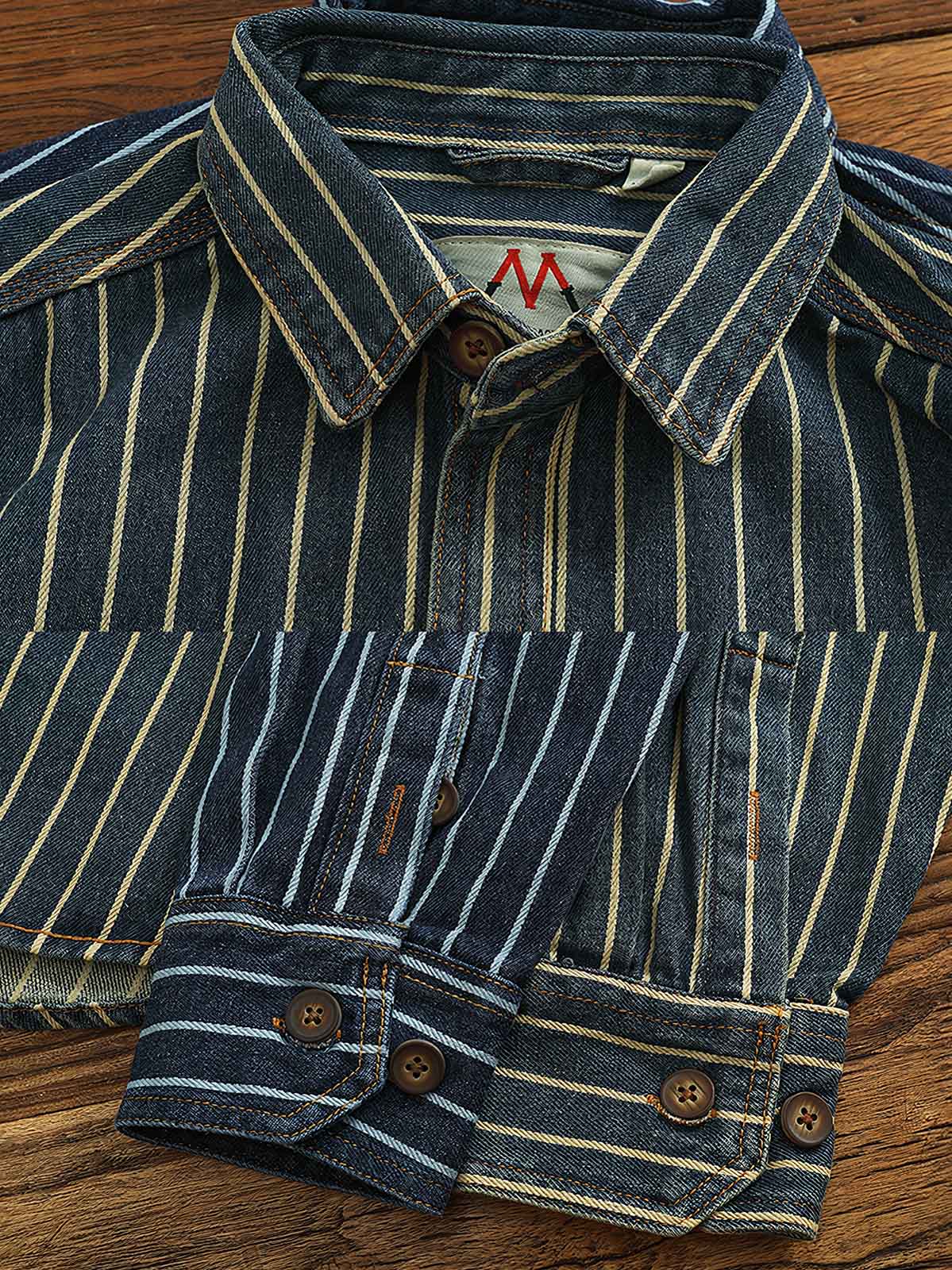 製品画像: ヘビーストライプデニムワークシャツの正面展示
詳細画像: 肘のパッチとストライプのディテールクローズアップ
モデル画像