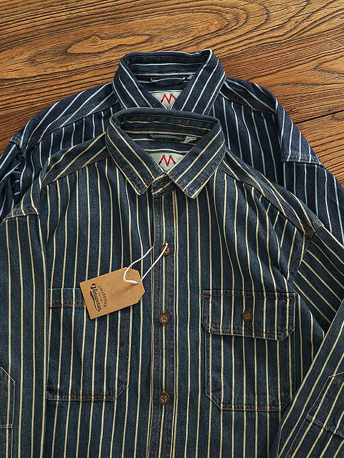 製品画像: ヘビーストライプデニムワークシャツの正面展示
詳細画像: 肘のパッチとストライプのディテールクローズアップ
モデル画像