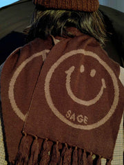 製品画像:
"柔らかい光沢感のあるウールスマイルマフラーの全体図。スマイルロゴとピースマークがデザインされた両面デザインが特徴的で、秋冬にぴったりな上品で快適なアクセサリー"
詳細画像:
"ジャカードフリンジと両面デザインの細部クローズアップ。シルクのような滑らかさを持つ光沢感のあるウール素材を使用し、立体感を引き立てる装飾"