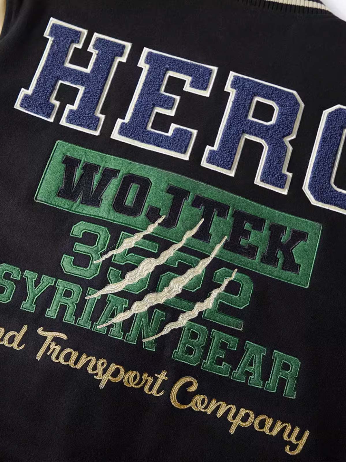 製品画像: HERO Wojtekヴィンテージ空軍ベースボールジャケットの全体画像、WWIIの英雄クマをテーマにしたデザイン
詳細画像: 背面の「HERO」とWojtekの刺繍ディテール、勇敢さと忠誠の象徴を示すデザイン