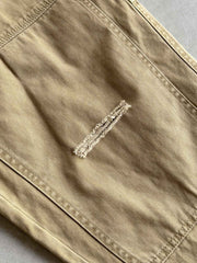 製品画像
「ヘビーウォッシュ加工が施されたヘリンボーン柄コットン素材のアメカジワークパンツ全体イメージ。自然な色褪せやダメージ感、パッチワークディテールが特徴。」
詳細画像
「ヘリンボーン柄コットン素材とヘビーウォッシュ加工によるダメージデザイン、パッチワークディテールをクローズアップ。YKK純銅ジッパーが耐久性を高める。」