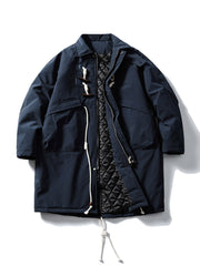 製品画像
牛角ボタン付きのロング丈中綿コート。クラシックなデザインと100%ナイロン素材による防風性が特徴で、高品質な中綿を使用した厚手の防寒コートの全体展示。冬のアウトドアや日常使いに最適。
詳細画像
牛角ボタンのディテールとドローコード付き立ち襟を特写。クラシックな雰囲気を醸し出すボタンデザインと、防寒性を高めるドローコードのディテールが際立つクローズアップ画像。