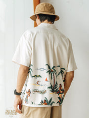 モデルが着用するビーチとヤシの木のレトロなハワイ風景プリントのアロハシャツ、自然で快適な着心地を示す。