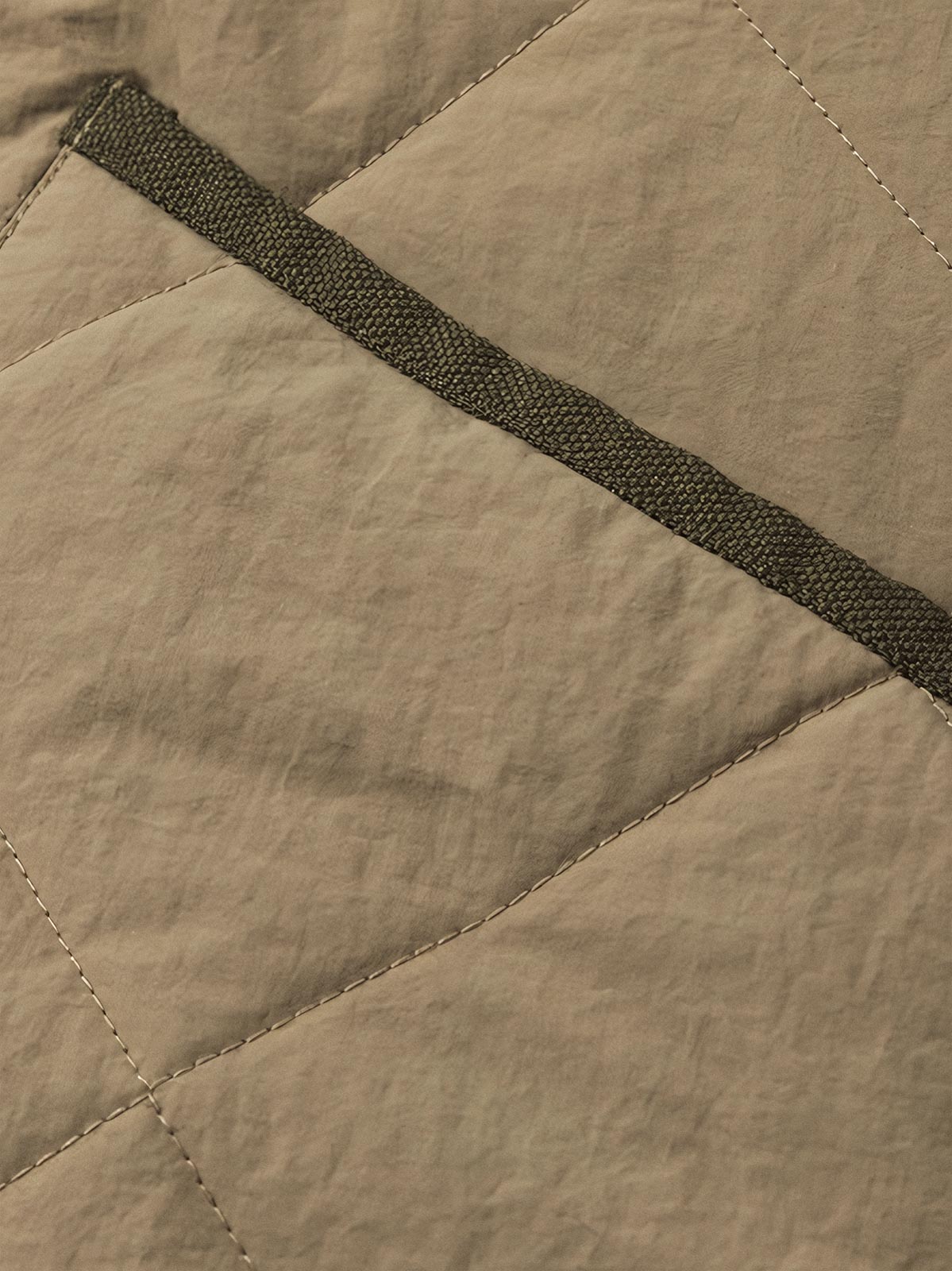 製品画像:クラシックなVネックデザインのキルティングチェック柄中綿ジャケット、100%ナイロン素材で防風性と耐裂性に優れた実用的なデザイン。秋冬に最適なシンプルで深みのあるスタイル。
詳細画像:精緻なチェック柄キルティング加工のディテール、耐久性と保温性を高める素材選び。中綿使用で軽量ながら適度な保温性を提供。