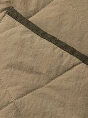 製品画像:クラシックなVネックデザインのキルティングチェック柄中綿ジャケット、100%ナイロン素材で防風性と耐裂性に優れた実用的なデザイン。秋冬に最適なシンプルで深みのあるスタイル。
詳細画像:精緻なチェック柄キルティング加工のディテール、耐久性と保温性を高める素材選び。中綿使用で軽量ながら適度な保温性を提供。