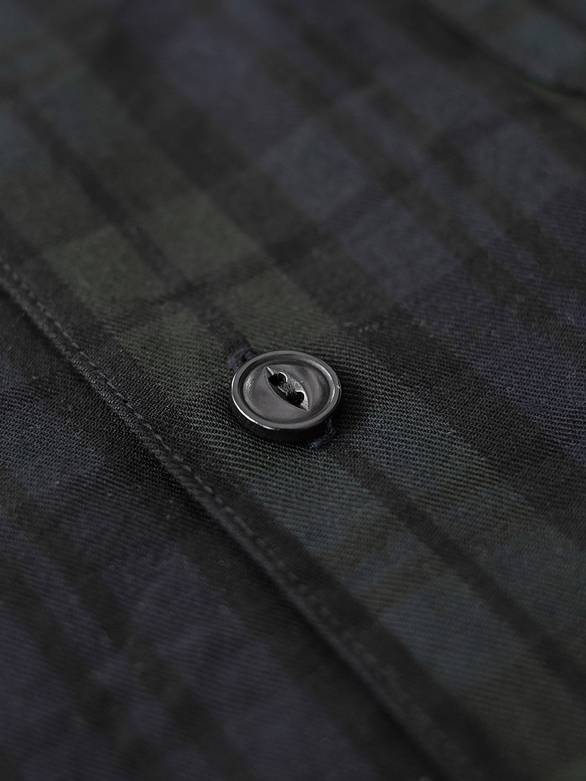 シャツのダークグリーン&ネイビーチェックのディテールとナチュラルキャッツアイボタンのクローズアップ