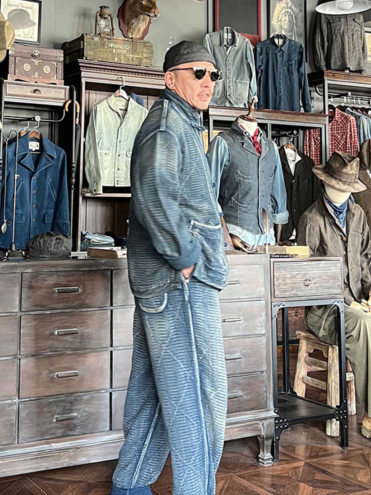 詳細画像: チャイナボタンのクラシックなディテールとストーンウォッシュ加工による深みのある藍色を強調した写真。
モデル画像: Indigo 藍染め スタンドカラーチャイナボタン コートを着用したモデルによる、洗練されたヴィンテージスタイルのコーディネート写真。