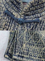 製品画像: 藍染め刺子織りピースワークスタンドカラージャケット全体写真。立ち襟とチャイナボタンが特徴の伝統とモダンが融合したデザイン。
詳細画像: 刺子織りの繊細なテクスチャと藍染めの深みある色合いを強調したディテール写真。水洗抜染加工による個性的な風合いを表現。