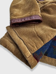 製品画像:アメリカンレトロスタイルのコーデュロイダブルブレストコートの正面図。厚手の生地で耐摩耗性に優れ、秋冬に最適。
詳細画像:ウシガシラボタンと本革で補強されたポケット口と袖口のディテール。アンカーデザインがレトロ感を引き立てます。