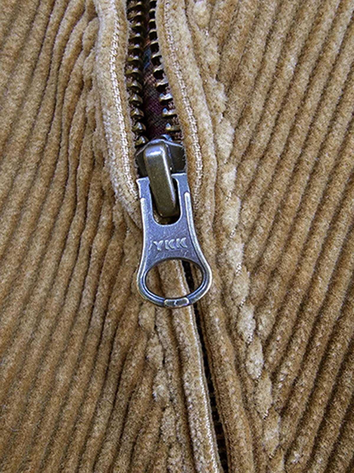 製品画像
クラシックなヴィンテージスタイルのコーデュロイ ワークジャケットの正面全体画像。特別なウォッシュ加工とショート丈デザインが特徴の一着。
詳細画像
YKK製の真鍮ジッパー、ブラスボタン、多ポケットデザイン、そしてコーデュロイ素材の独特な風合いをクローズアップした画像。質感とヴィンテージ感を際立たせたディテール。