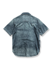 レトロなウォッシュとブリーチ処理が施されたパッチポケット付きのデニム半袖シャツの正面ビュー。ゆったりとしたストレートフィットで、肩部分にパッチデザインと貝殻ボタンが特徴的です。