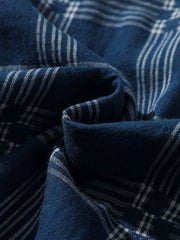 チェック柄キューバンカラーシャツの細部、特に精緻に縫製されたポケットと洗練されたボタンディテールが特徴です。