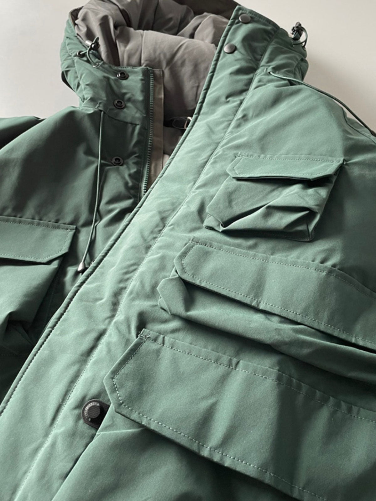 製品画像: 防水ヘビーボア付きアウトドアジャケットの正面画像、防寒性と多機能ポケットが特徴。
詳細画像: 多ポケットと防水素材のディテール画像、アウトドアでの利便性と耐久性を強調。