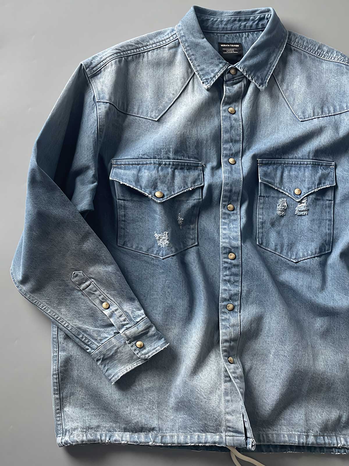 製品画像: 古着風加工の破れ水洗いヴィンテージデニムシャツ正面画像、ヴィンテージ感が際立つ。
詳細画像: ワークポケットと摩耗加工のディテール画像、クラシックな雰囲気を強調。