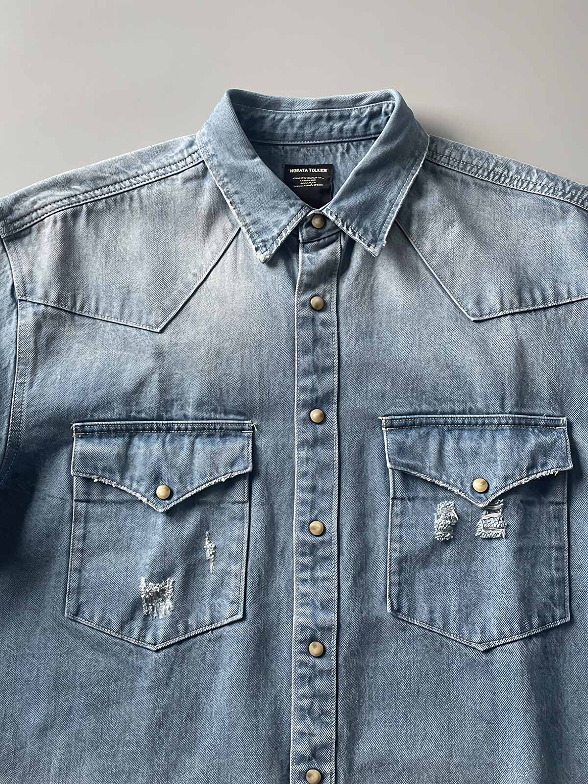 製品画像: 古着風加工の破れ水洗いヴィンテージデニムシャツ正面画像、ヴィンテージ感が際立つ。
詳細画像: ワークポケットと摩耗加工のディテール画像、クラシックな雰囲気を強調。