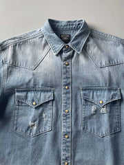 製品画像: 古着風加工の破れ水洗いヴィンテージデニムシャツ正面画像、ヴィンテージ感が際立つ。
詳細画像: ワークポケットと摩耗加工のディテール画像、クラシックな雰囲気を強調。