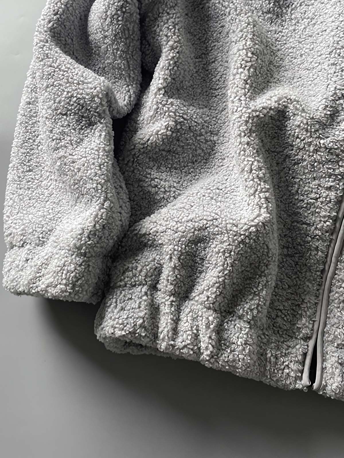 製品画像: ボアフリーススタンドカラージャケットの全体画像、アウトドアやカジュアルスタイルに対応。
詳細画像: 胸元ジッパーポケットのディテール画像、実用性とデザイン性を強調。