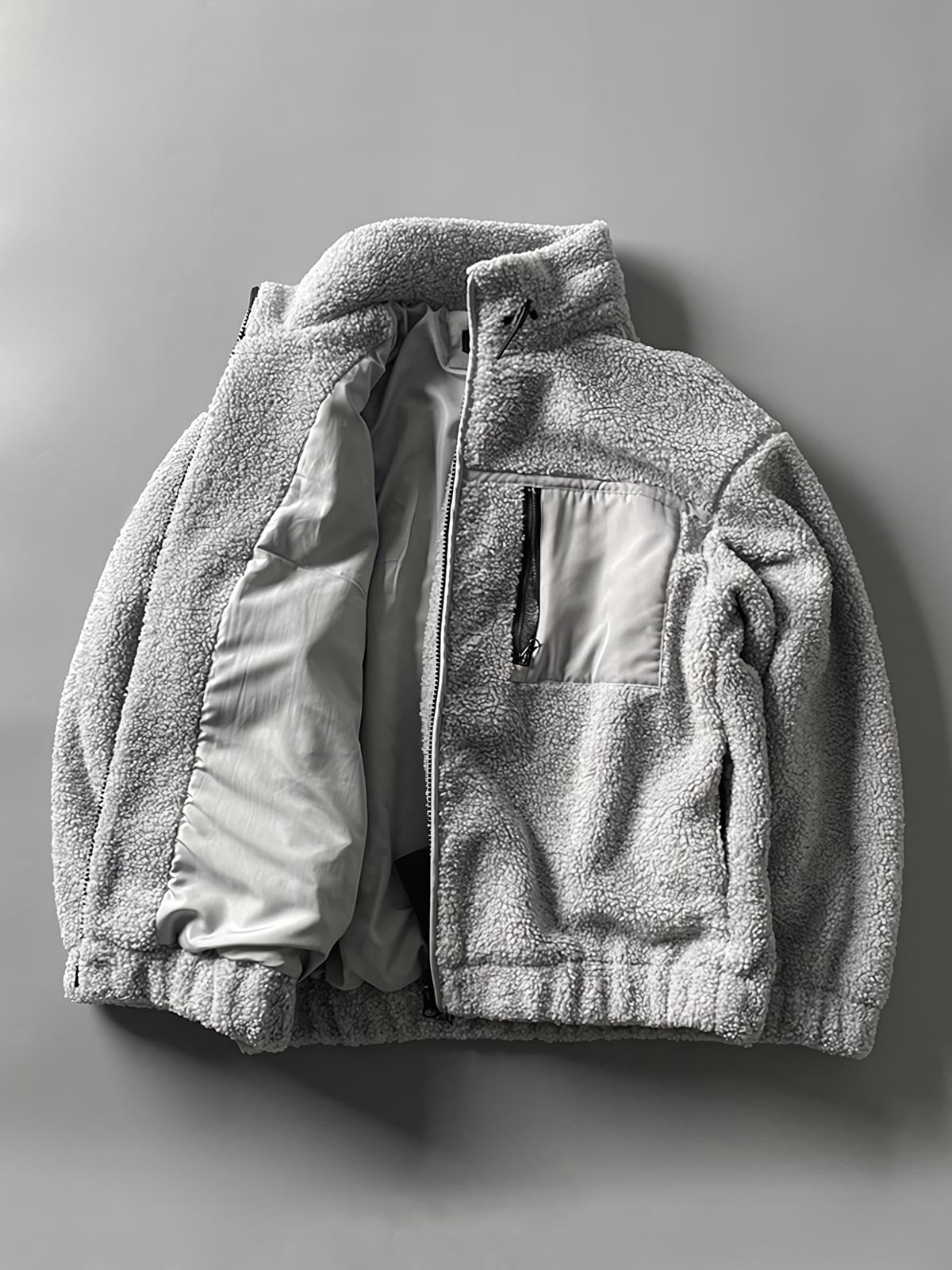 製品画像: ボアフリーススタンドカラージャケットの全体画像、アウトドアやカジュアルスタイルに対応。
詳細画像: 胸元ジッパーポケットのディテール画像、実用性とデザイン性を強調。