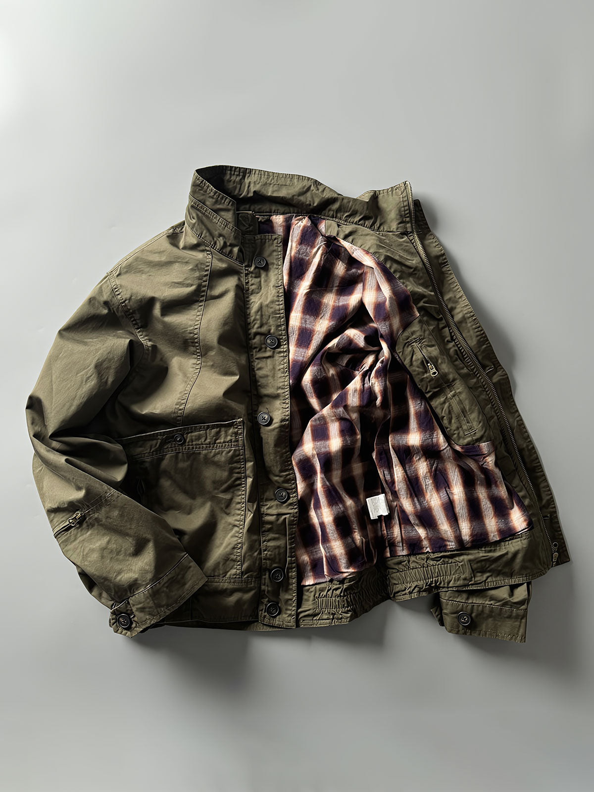 製品画像: オレンジカラーのダブルスタンドカラーワークジャケットの正面画像、実用的でスタイリッシュなデザインが特徴。
詳細画像: 袖部のジッパーポケットとスタンドカラーデザインのディテール画像、ワークスタイルを強調。