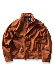 製品画像: オレンジカラーのダブルスタンドカラーワークジャケットの正面画像、実用的でスタイリッシュなデザインが特徴。
詳細画像: 袖部のジッパーポケットとスタンドカラーデザインのディテール画像、ワークスタイルを強調。