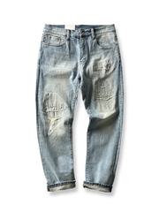 製品画像: ヴィンテージ風破れ加工・パッチ付きデニムパンツ全体画像、ライトブルーのウォッシュ加工とストリート感あふれるデザイン
詳細画像: 破れ加工、パッチディテールのクローズアップ、ヴィンテージ風デニムパンツのディテール、セルビッジデザインが特徴