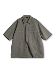 軽量シアサッカー生地を使用した2ポケットワークシャツ。小さめ襟と5ボタン仕様、背面にレーザー木製プレートと琥珀ボタンがアクセントの涼しげでモダンなデザイン。