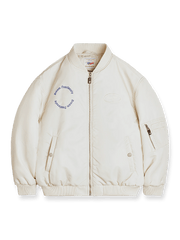 ウォームベージュのナイロンMA‑1フライトジャケット。ベルクロパッチ、Dreamスローガン、レザープル付きアームポケットジッパーを特徴とするアイテム。