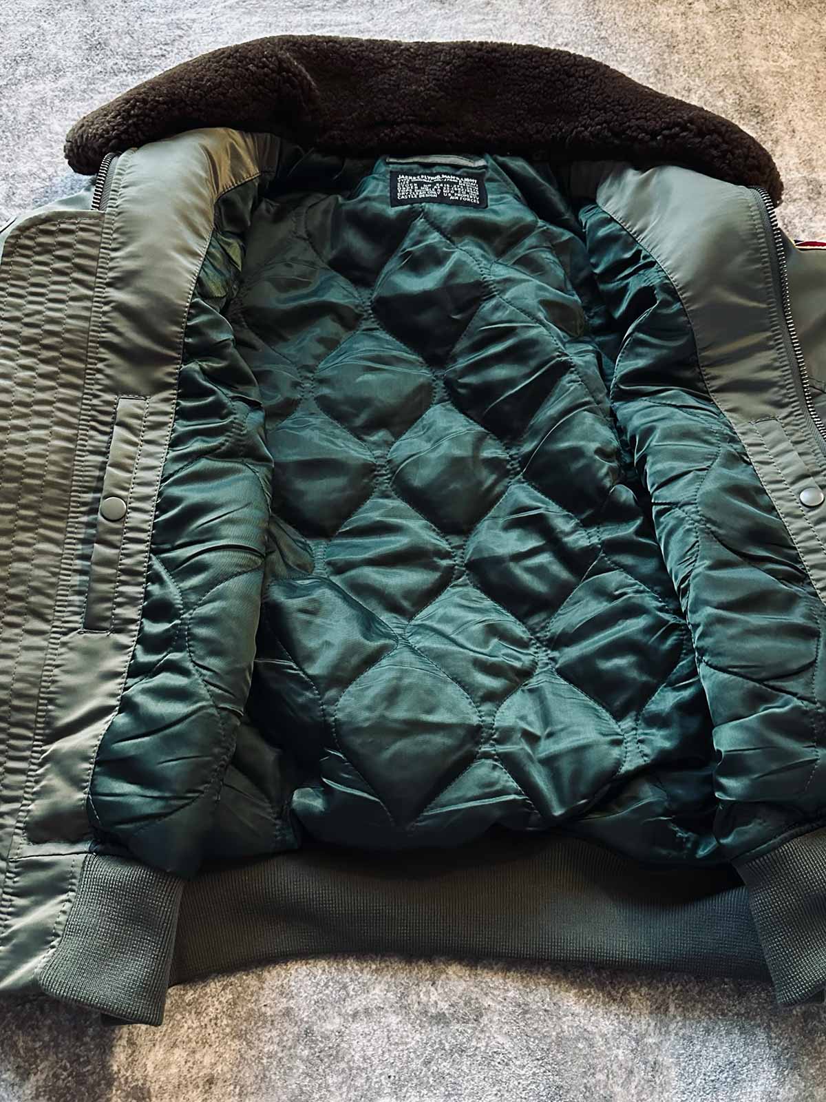 製品画像: B-15Dフライトジャケットの正面画像
詳細画像: 取り外し可能なファー襟とメタルパーツ、ジッパーのディテール