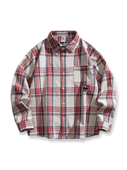 胸元にバッジを配したアメリカンヴィンテージ風チェック柄長袖シャツ。100%コットン素材とルーズフィットシルエットを特徴とするアイテム。