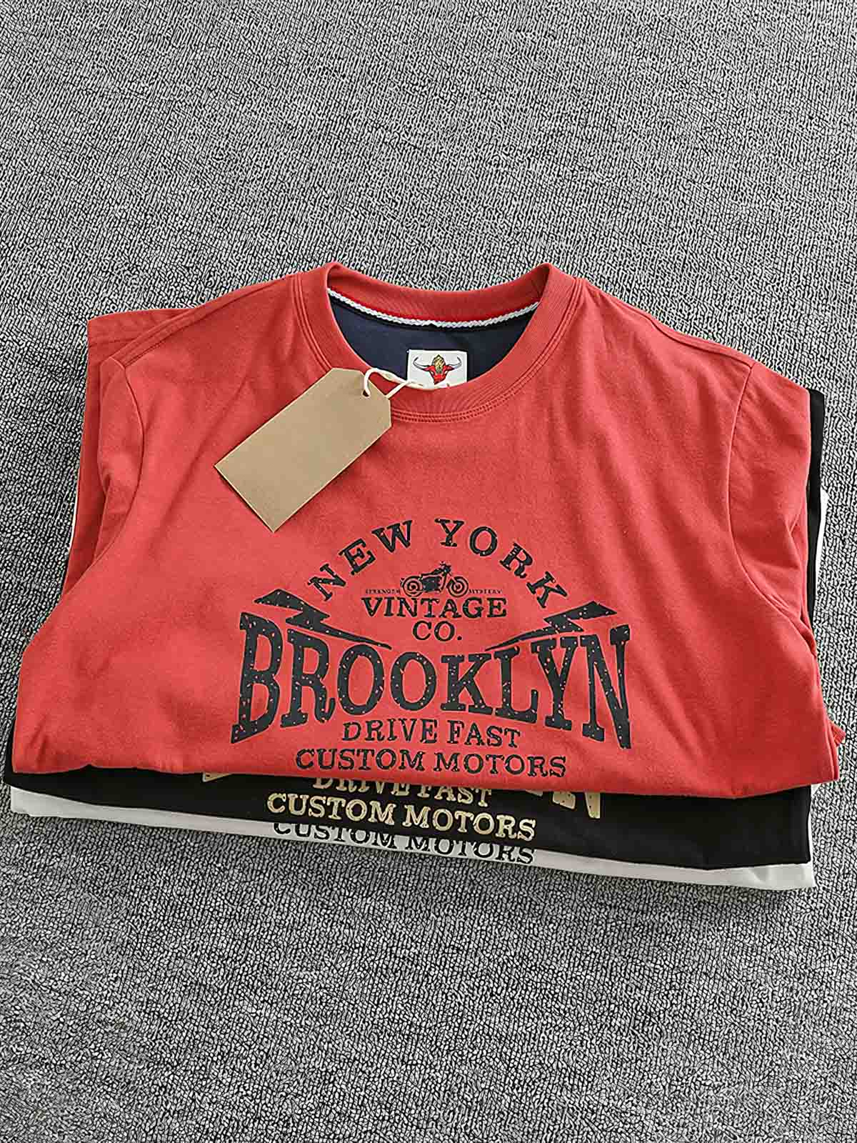 製品画像: BROOKLYNヴィンテージプリント長袖Tシャツの全体展示 詳細画像: Tシャツの裾にあるパッチワークデザインのディテール