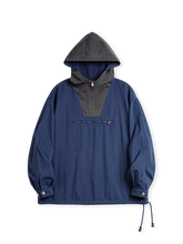 旧式軍服をモチーフにしたプルオーバーフードと台形カラーブロックが特徴のデッキジャケット。実用的なジッパーポケットや調節可能な袖口付き。
