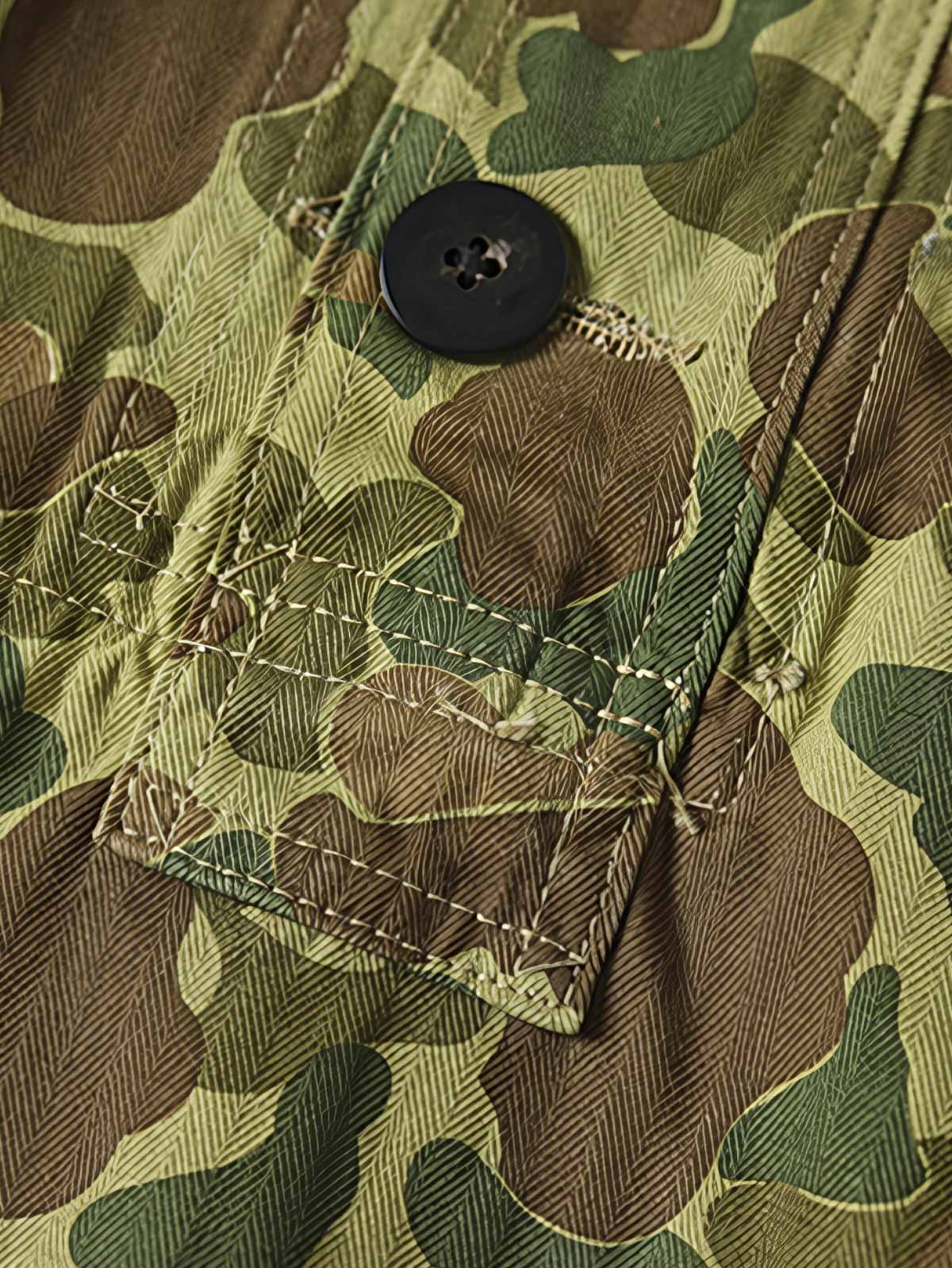 製品画像: 迷彩柄ツイルデニム生地の砲兵防護プルオーバーパーカー復刻バージョンの正面画像。
詳細画像: 大きなフードと三層前立てデザインのディテール特写。機能性とヴィンテージ感が際立つディテール。