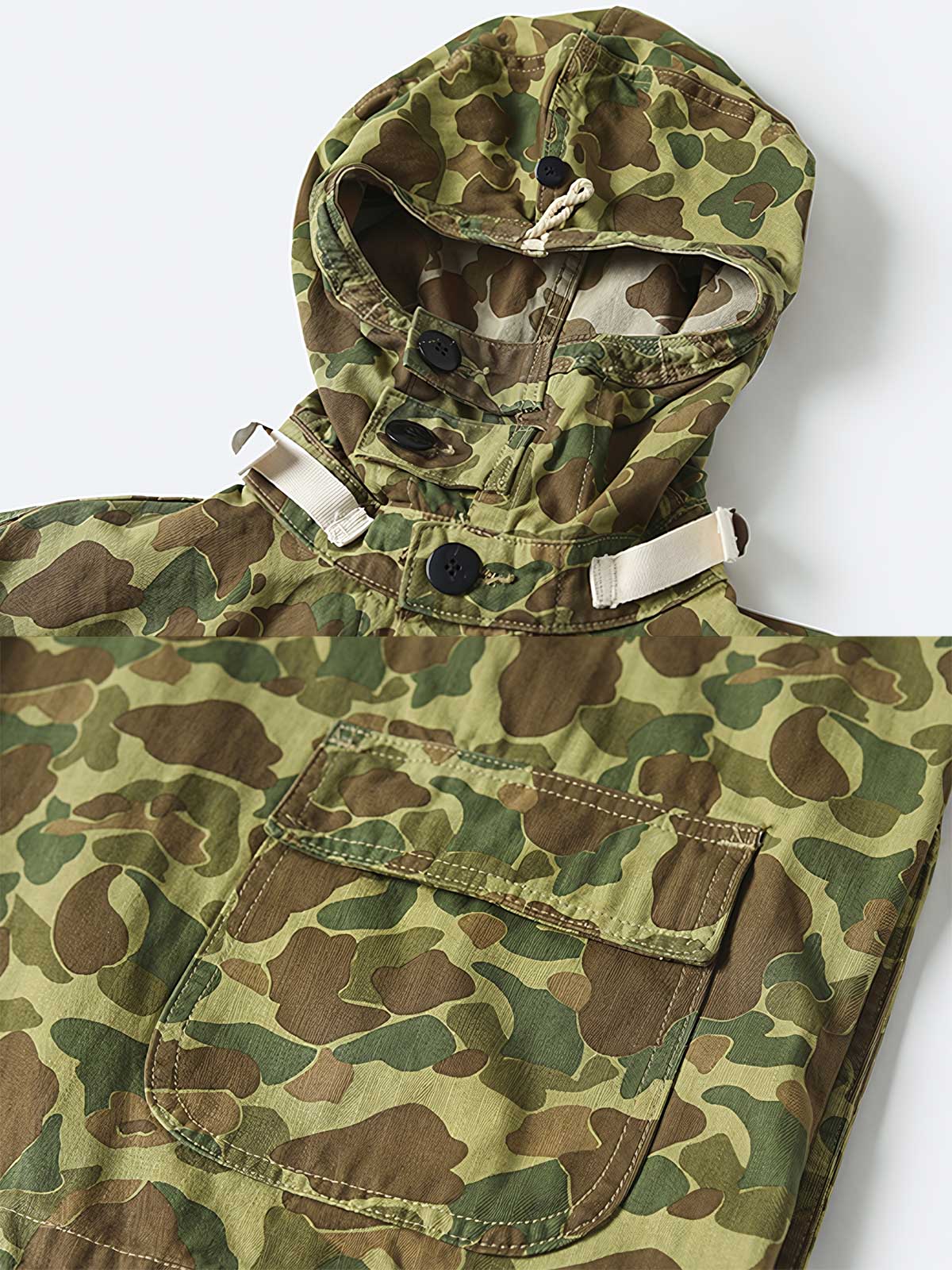 製品画像: 迷彩柄ツイルデニム生地の砲兵防護プルオーバーパーカー復刻バージョンの正面画像。
詳細画像: 大きなフードと三層前立てデザインのディテール特写。機能性とヴィンテージ感が際立つディテール。