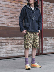 詳細画像: 大きなフードと三層前立てデザインのディテール特写。機能性とヴィンテージ感が際立つディテール。
モデル画像: モデルが迷彩柄砲兵防護プルオーバーパーカーを着用したスタイリング例。戦時風デザインを取り入れたコーディネート。