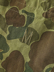 製品画像: 迷彩柄ツイルデニム生地の砲兵防護プルオーバーパーカー復刻バージョンの正面画像。
詳細画像: 大きなフードと三層前立てデザインのディテール特写。機能性とヴィンテージ感が際立つディテール。