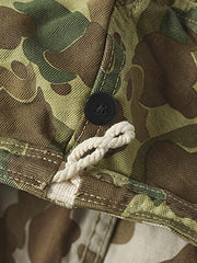 製品画像: 迷彩柄ツイルデニム生地の砲兵防護プルオーバーパーカー復刻バージョンの正面画像。
詳細画像: 大きなフードと三層前立てデザインのディテール特写。機能性とヴィンテージ感が際立つディテール。