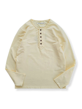 ヘンリーネックとボタンディテールが特徴の米色の100%コットン長袖Tシャツの全体像。