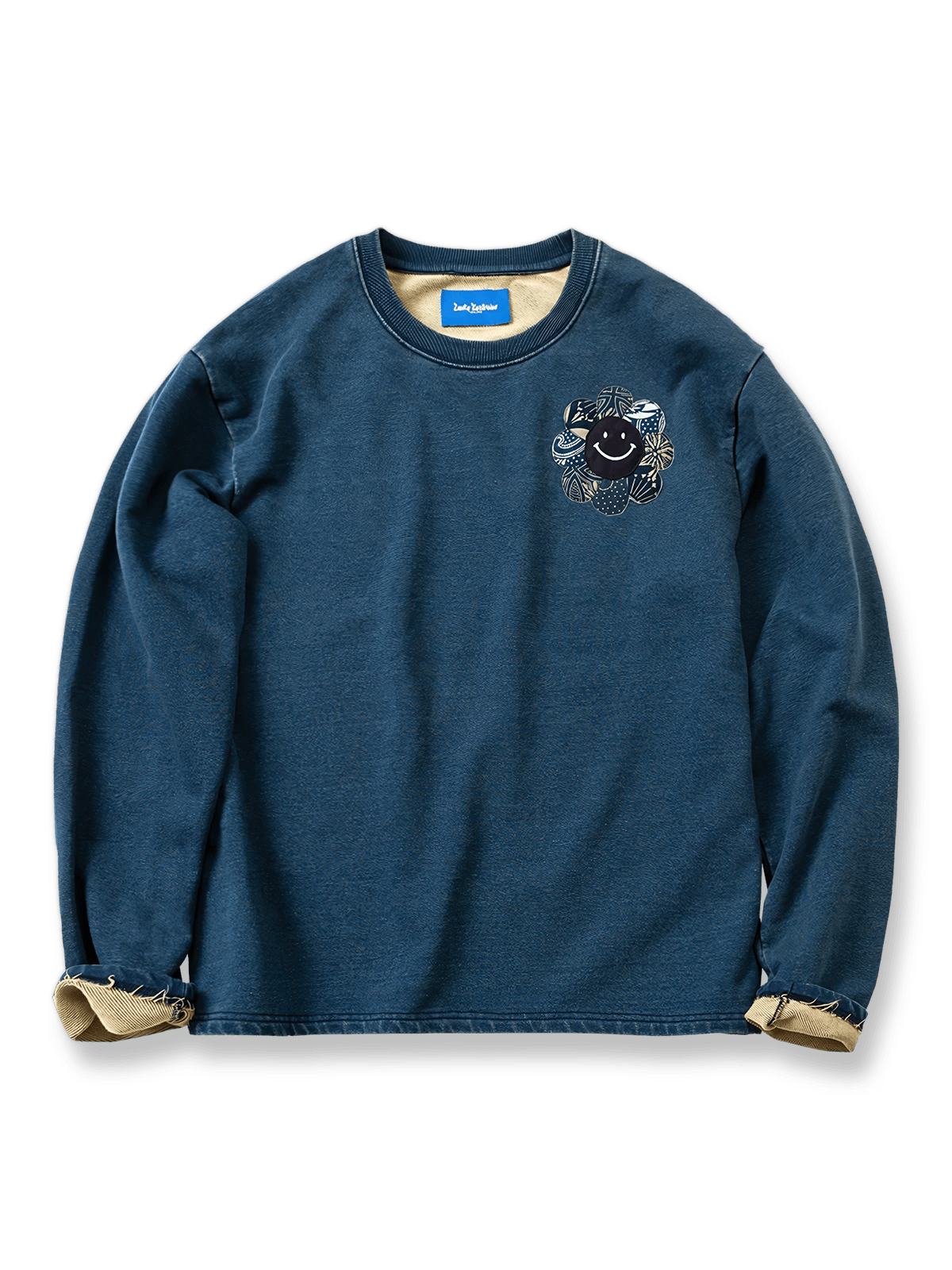 インディゴ染めスウェットにスマイリーフラワー刺繍と古着風パッチワークを施したデザイン。