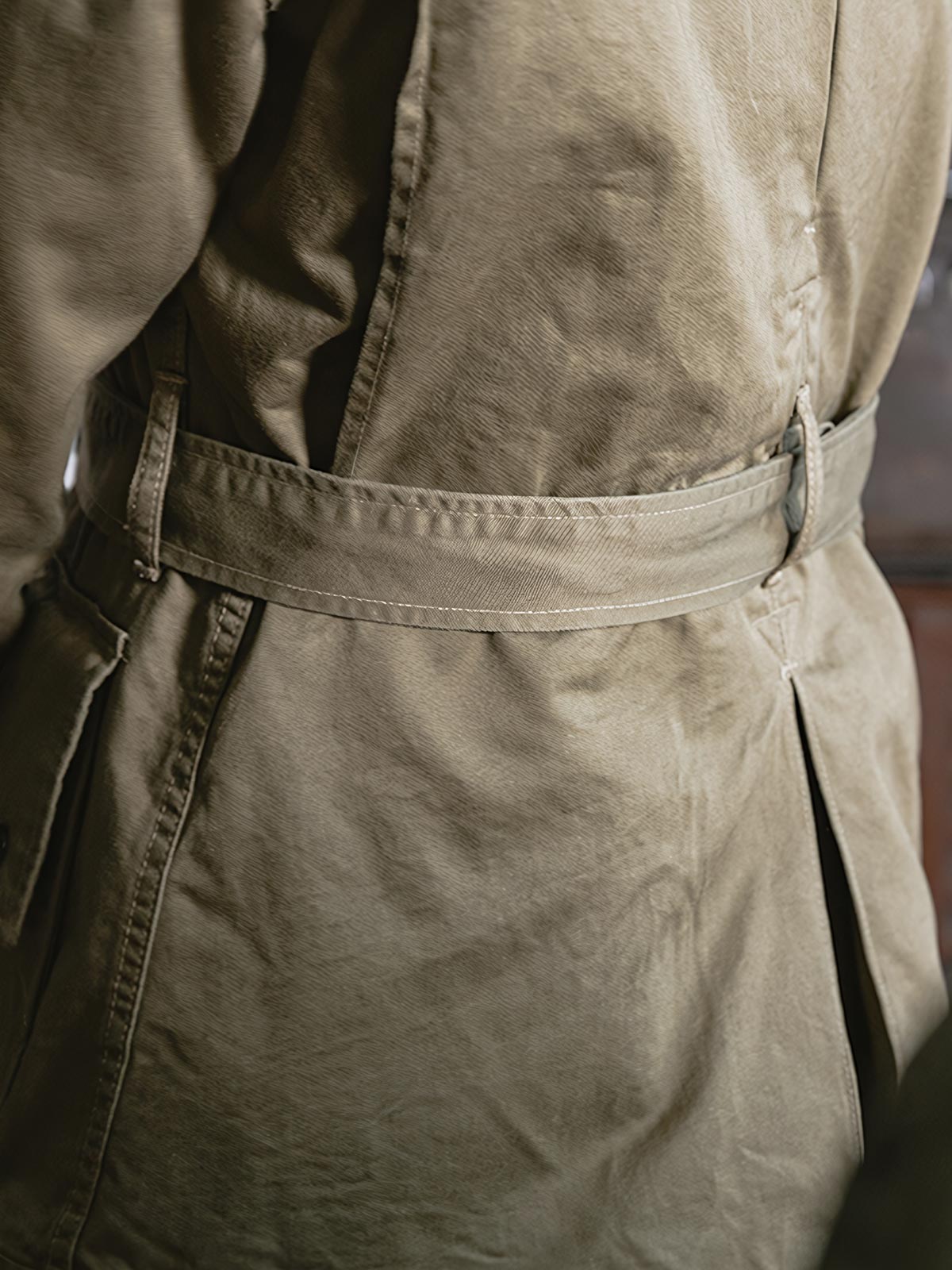 製品画像: M-42パラシュートジャケットの正面画像。ヴィンテージミリタリースタイルが際立つ高光沢ツイルコットンジャケット。
詳細画像: ジャケットのポケットとウエストベルトのディテール。機能性とデザイン性を兼ね備えたディテール。