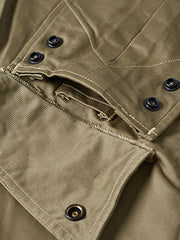 製品画像: M-42パラシュートジャケットの正面画像。ヴィンテージミリタリースタイルが際立つ高光沢ツイルコットンジャケット。
詳細画像: ジャケットのポケットとウエストベルトのディテール。機能性とデザイン性を兼ね備えたディテール。