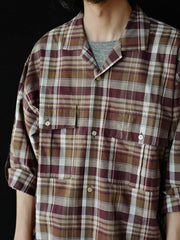 詳細画像: キューバンカラーと胸前のフラップポケットのディテール。チェック柄の鮮明さとシャツの質感を強調。
モデル画像: モデルがMADRAS (マドラス) チェック柄シャツを着用したスタイリング例。実際の着用感やフィット感を視覚的に伝える。