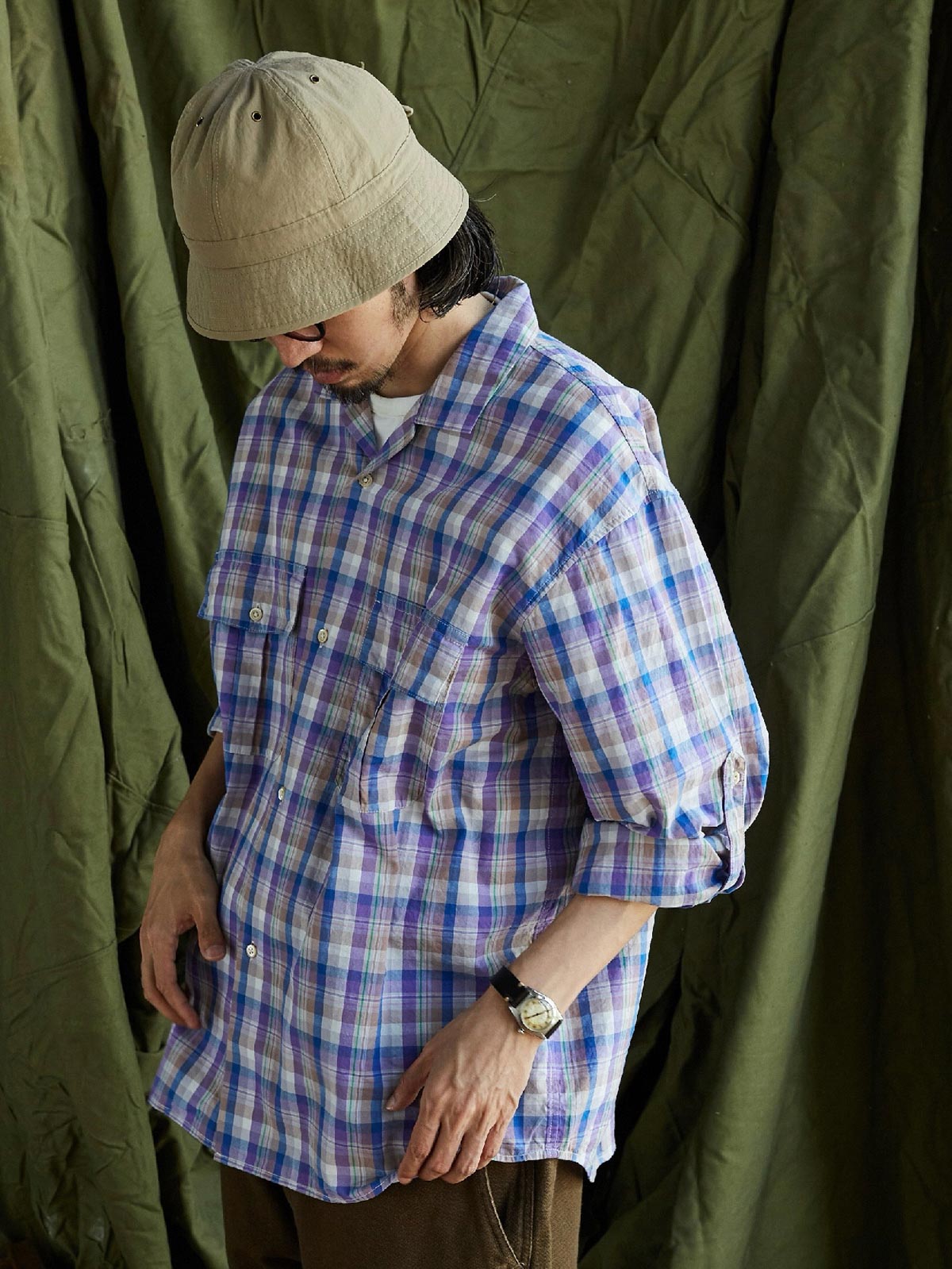 詳細画像: キューバンカラーと胸前のフラップポケットのディテール。チェック柄の鮮明さとシャツの質感を強調。
モデル画像: モデルがMADRAS (マドラス) チェック柄シャツを着用したスタイリング例。実際の着用感やフィット感を視覚的に伝える。